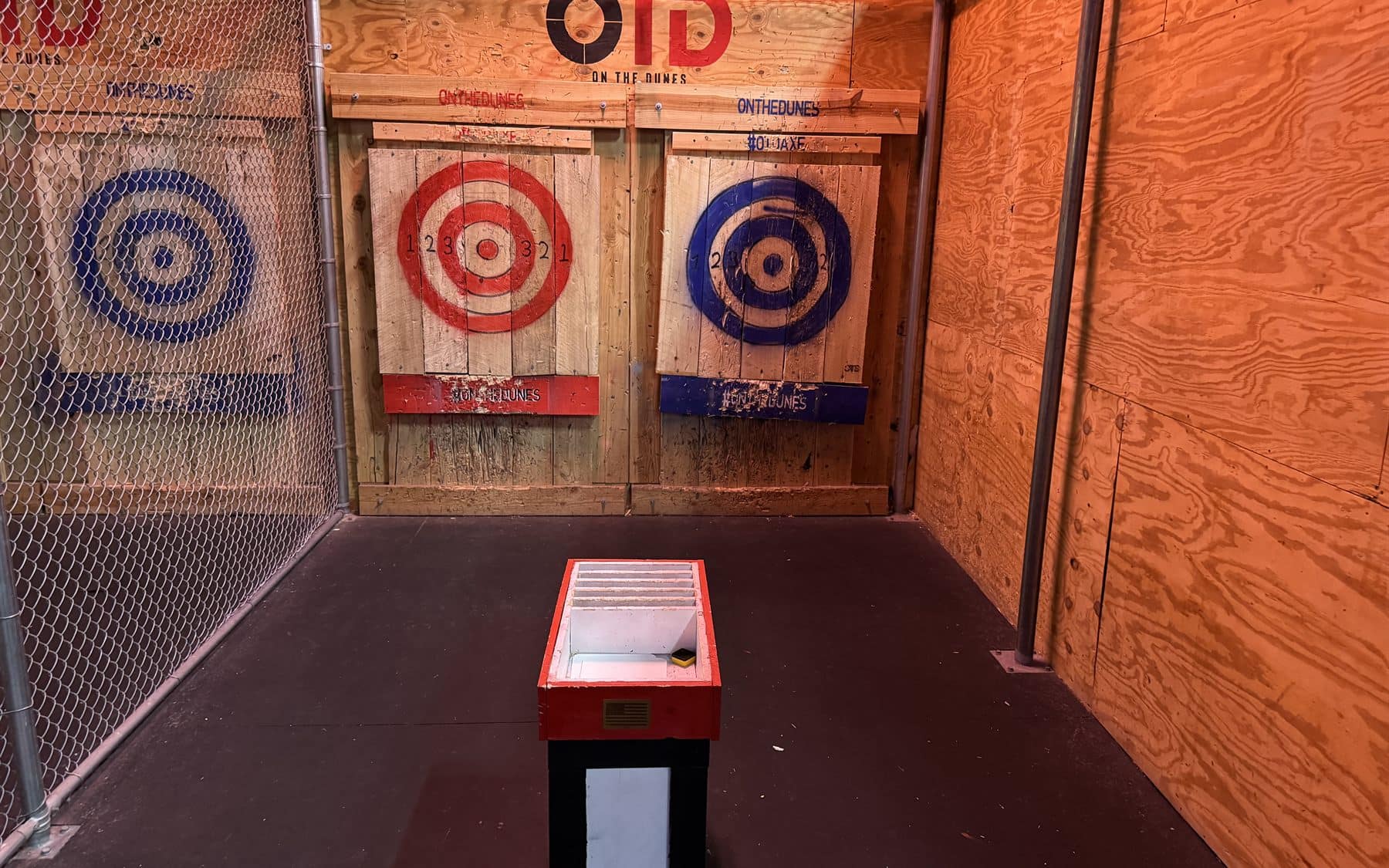 Axe throwing targets inside a wood-lined throwing stall at On The Dunes Sports
